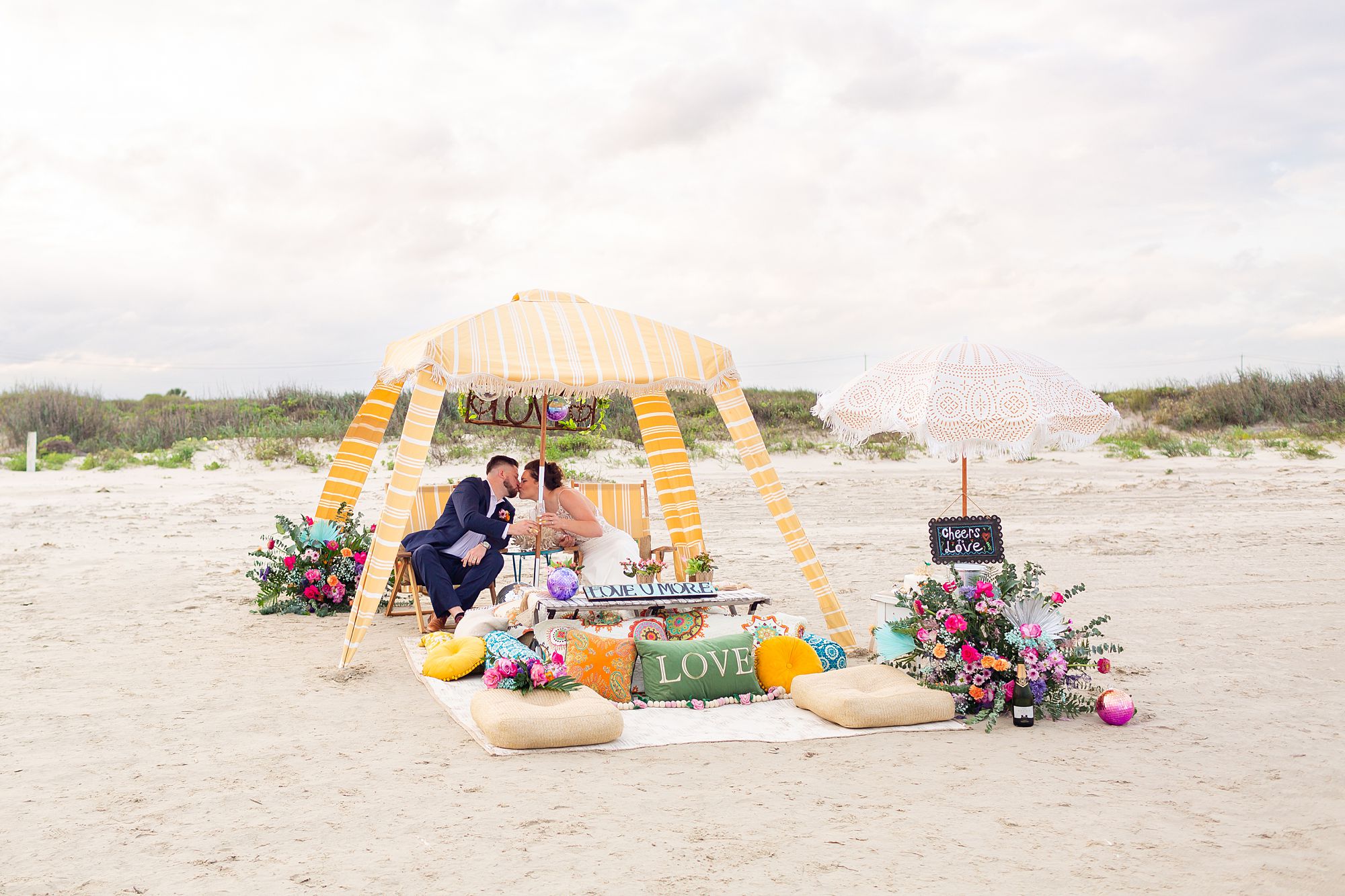 A bride and groom share a kiss during a beach picnic on Galveston Island.