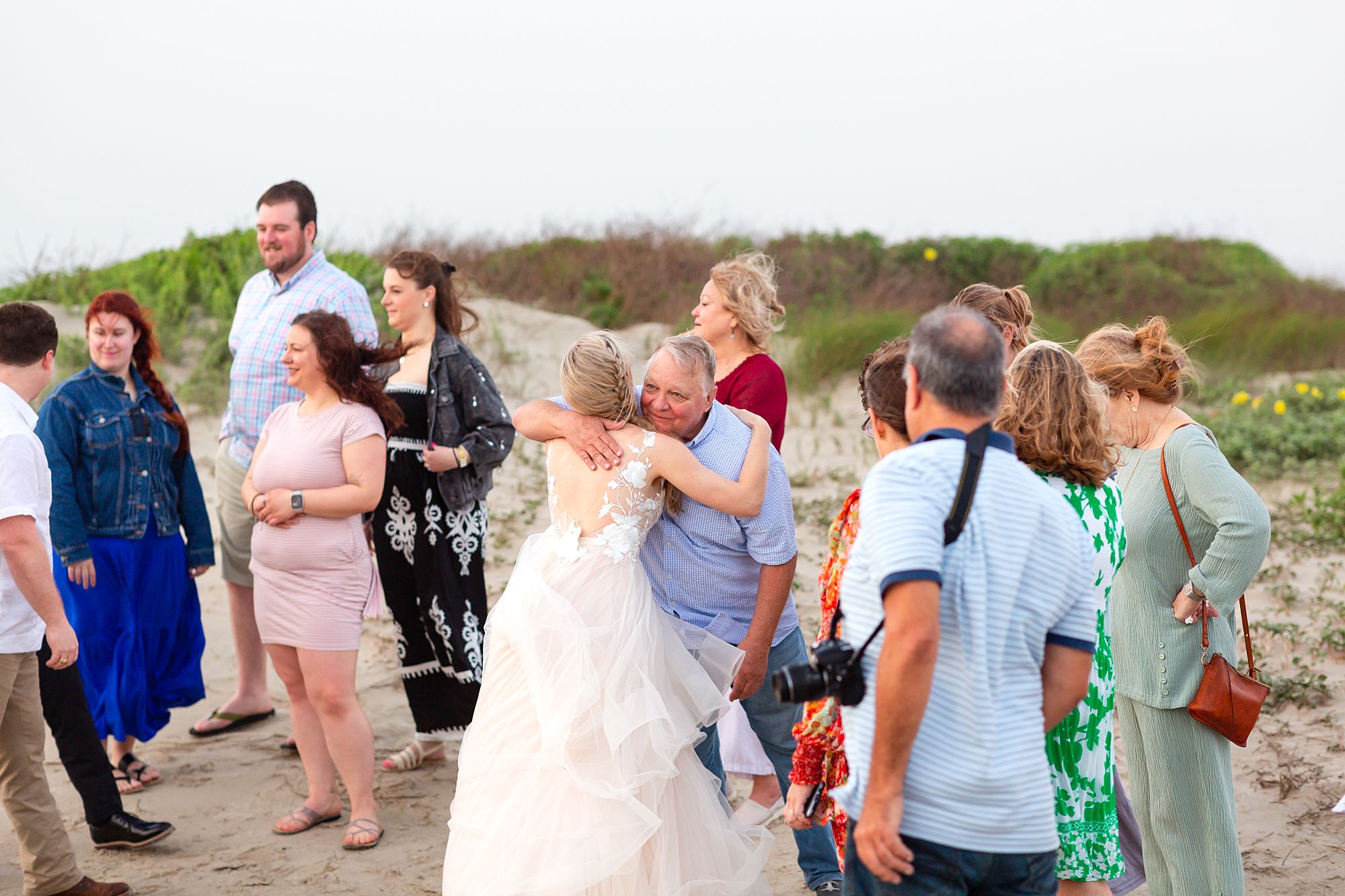 A bride and groom hug guests after their elopement ceremony on a beach on Galveston Island.